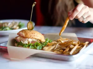 A person is eating food from a white tray.