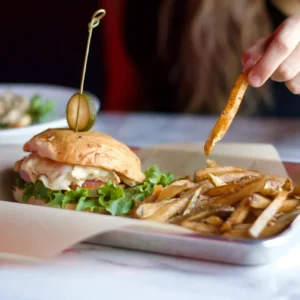 A person is eating food from a white tray.