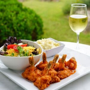 A bowl of food and some wine on the table.