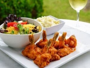A bowl of food and some wine on the table.